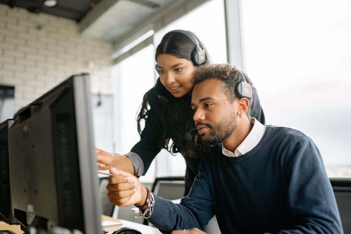 Call center agents with headsets reviewing information on a computer screen together